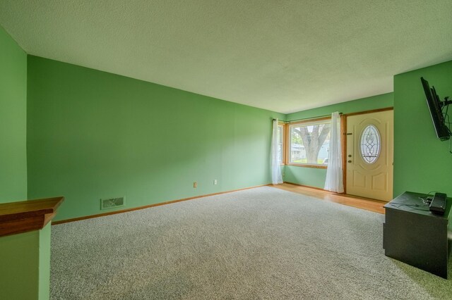 foyer with a textured ceiling and light carpet