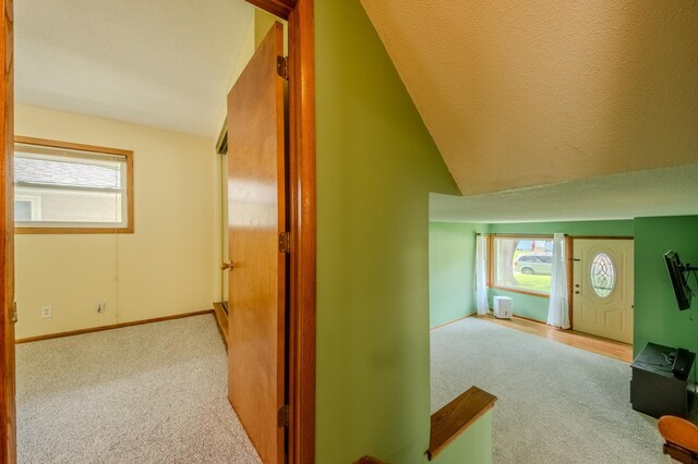 hallway featuring a textured ceiling, a wealth of natural light, and lofted ceiling