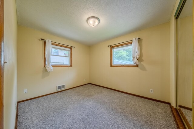 unfurnished room featuring carpet flooring and a textured ceiling