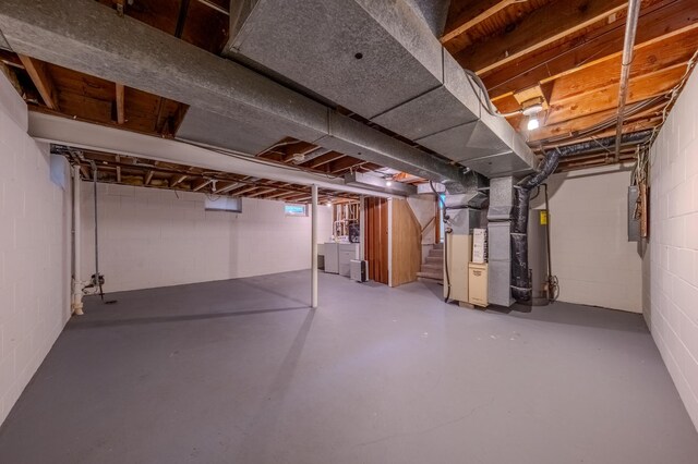 basement with electric panel, heating unit, and washer and clothes dryer