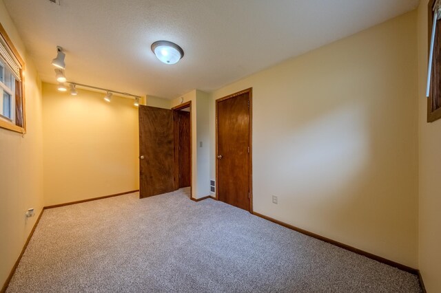 carpeted spare room featuring rail lighting