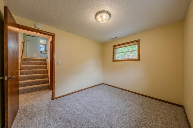 carpeted empty room featuring a textured ceiling