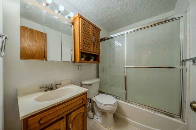 full bathroom with tile patterned floors, a textured ceiling, vanity, enclosed tub / shower combo, and toilet