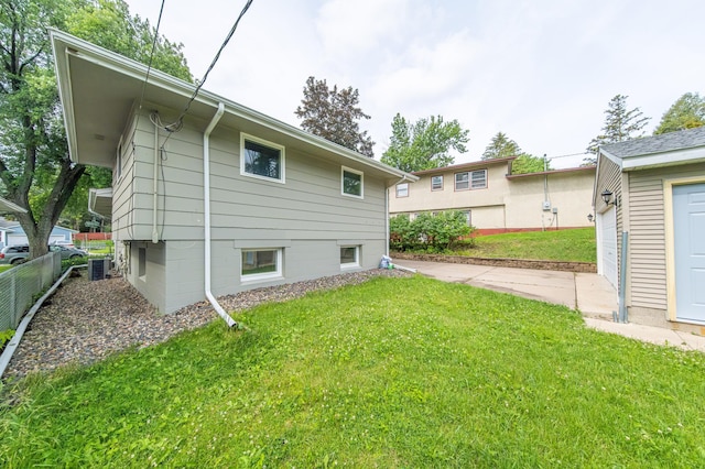 rear view of property featuring central AC, a garage, and a lawn