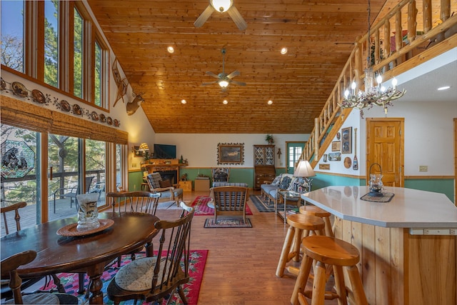 dining space featuring wood-type flooring, ceiling fan with notable chandelier, wood ceiling, and high vaulted ceiling