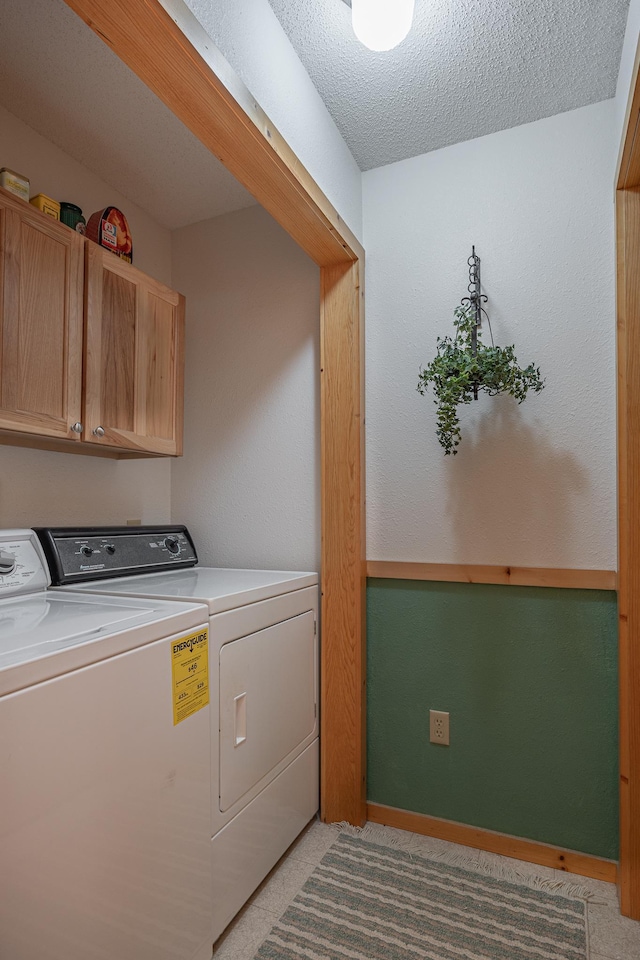 laundry area with cabinets, a textured ceiling, and washing machine and dryer