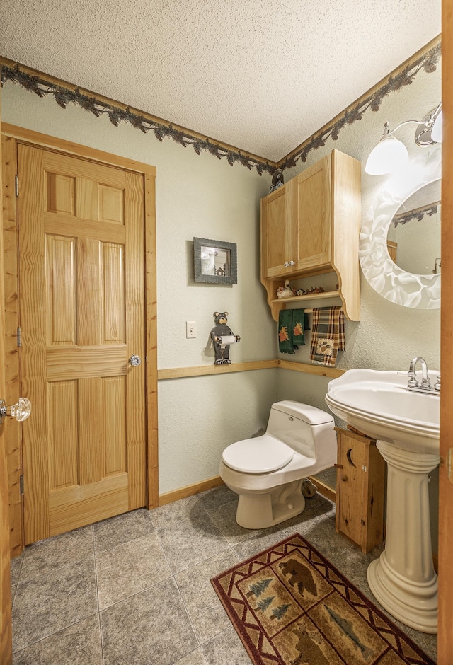 bathroom with tile patterned flooring, toilet, and a textured ceiling