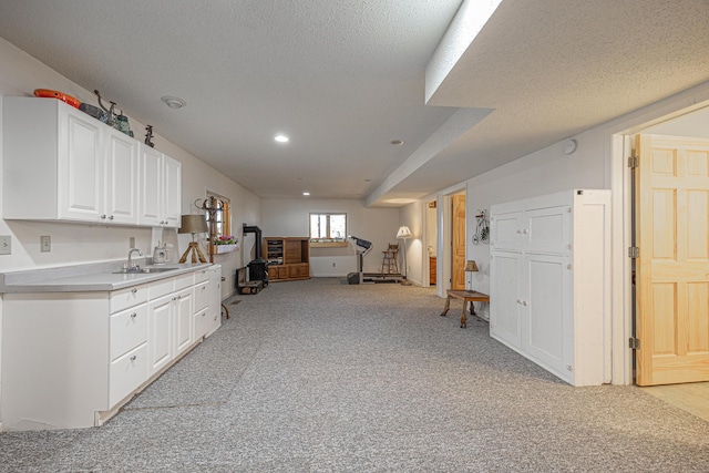 kitchen with light colored carpet, a textured ceiling, sink, and white cabinetry