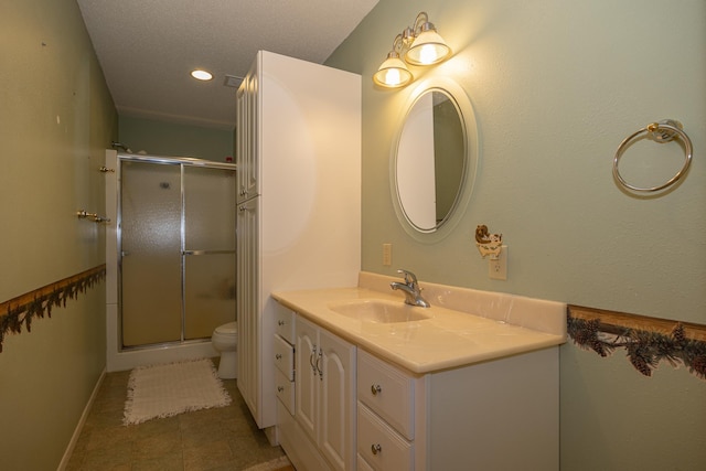 bathroom featuring tile patterned flooring, vanity, a shower with door, and toilet