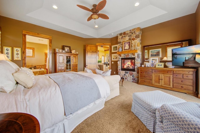 bedroom with light colored carpet, ceiling fan, and a tray ceiling