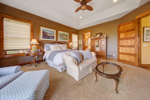 bedroom with ceiling fan, a tray ceiling, and carpet