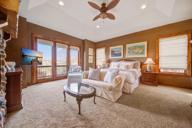 bedroom with access to outside, a raised ceiling, ceiling fan, and light carpet