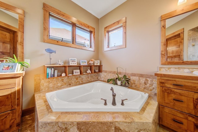 bathroom featuring a relaxing tiled tub and vanity