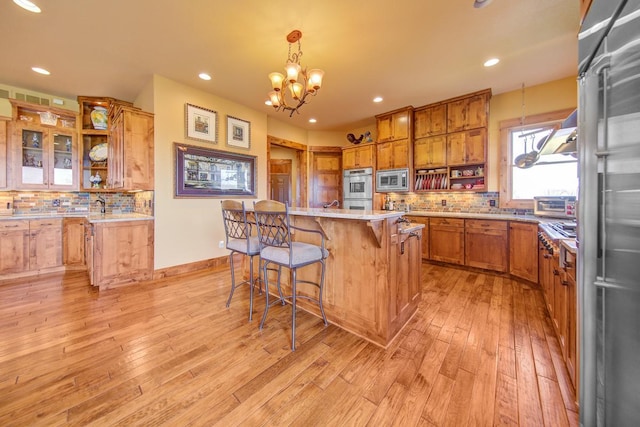 kitchen featuring decorative light fixtures, stainless steel microwave, a notable chandelier, and a center island