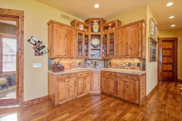 kitchen featuring light stone counters, hardwood / wood-style floors, and backsplash