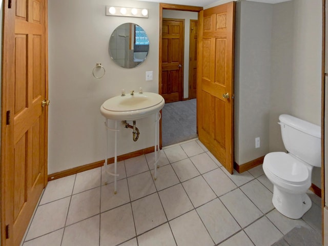 bathroom with toilet, sink, and tile patterned floors