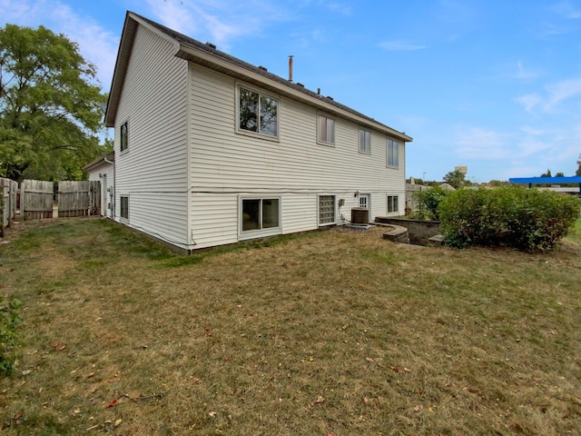 back of property with a yard and central AC