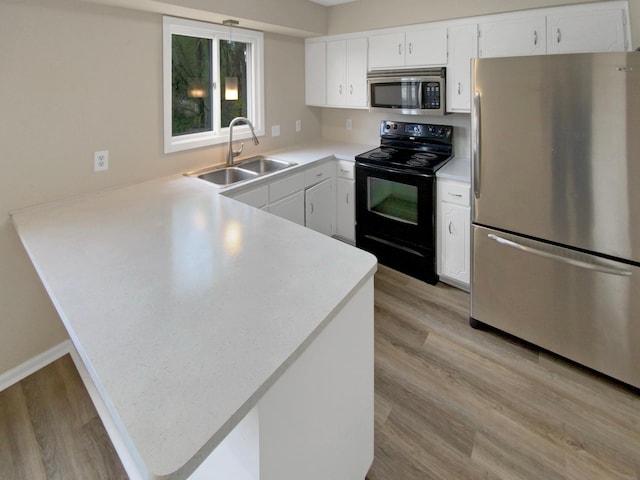 kitchen featuring sink, stainless steel appliances, light wood-type flooring, and kitchen peninsula