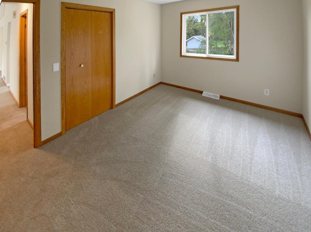 unfurnished bedroom featuring light colored carpet and a closet