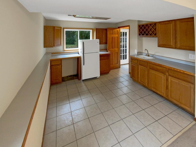 kitchen featuring sink, light tile patterned floors, and white fridge