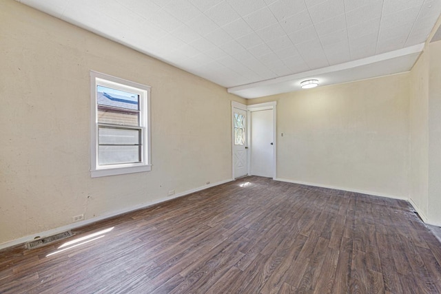 spare room featuring baseboards, visible vents, a healthy amount of sunlight, and wood finished floors