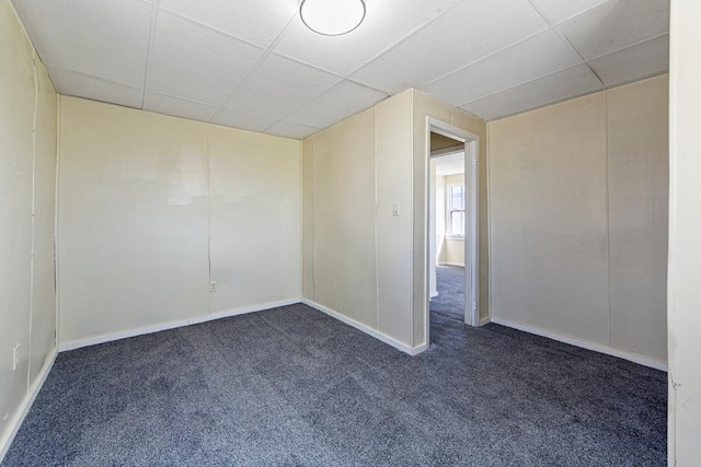 spare room featuring a drop ceiling and dark carpet