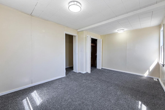 interior space featuring baseboards, a closet, and dark carpet
