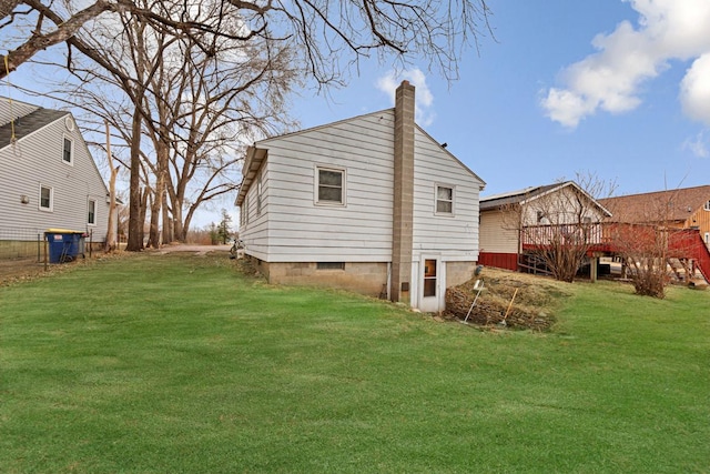 rear view of property with a lawn, a chimney, and a deck