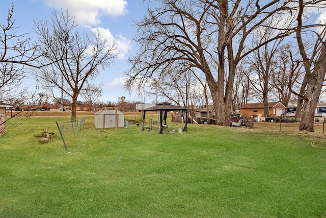 view of yard featuring a gazebo, an outbuilding, fence, and a storage shed