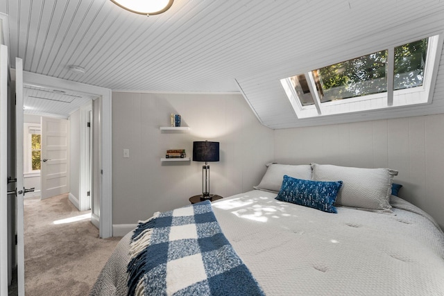 carpeted bedroom featuring vaulted ceiling with skylight