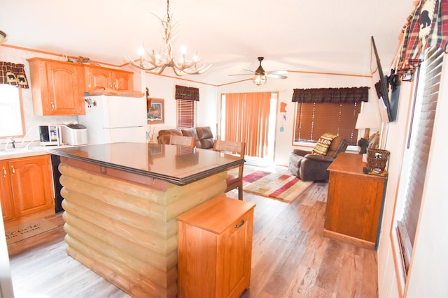 kitchen featuring pendant lighting, a center island, ceiling fan with notable chandelier, white refrigerator, and light wood-type flooring