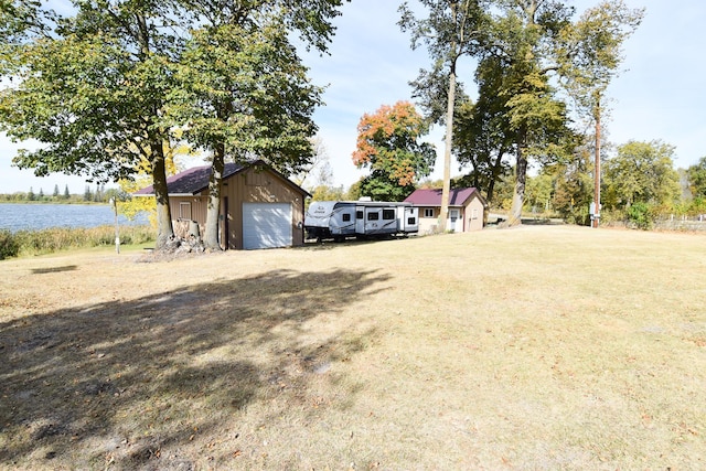 view of front of home featuring a front yard, a water view, an outdoor structure, and a garage