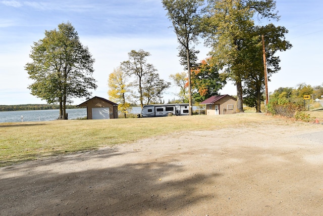 view of yard featuring a water view, an outdoor structure, and a garage