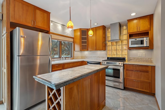 kitchen featuring wall chimney exhaust hood, stainless steel appliances, sink, a center island, and hanging light fixtures