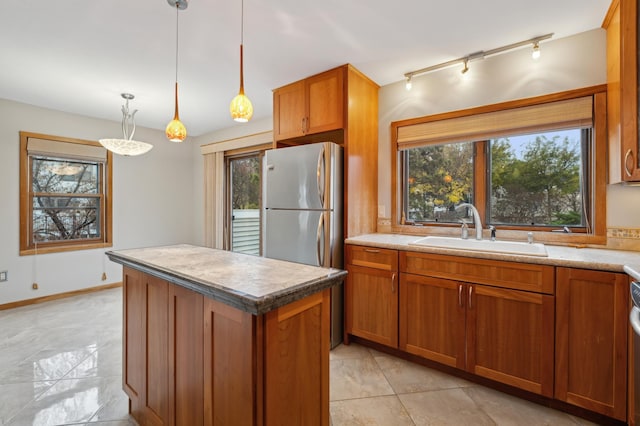 kitchen featuring stainless steel fridge, sink, a healthy amount of sunlight, and decorative light fixtures