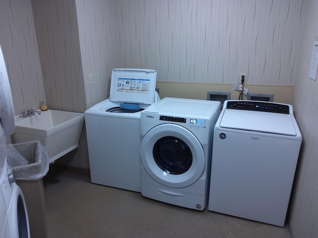 clothes washing area featuring wooden walls, sink, and washer and dryer