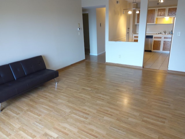 unfurnished living room featuring sink and light hardwood / wood-style floors