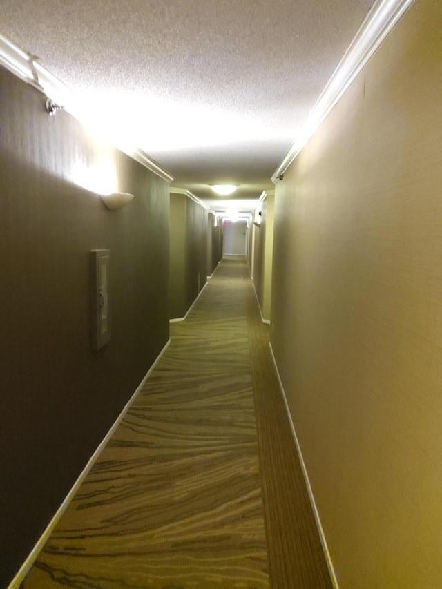 hallway featuring dark hardwood / wood-style flooring, crown molding, and a textured ceiling