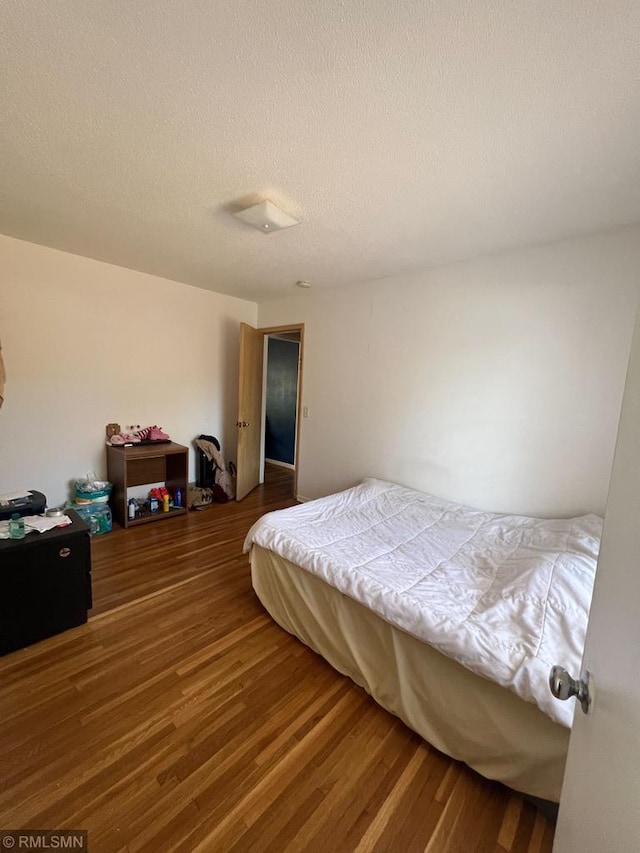 bedroom with hardwood / wood-style floors and a textured ceiling