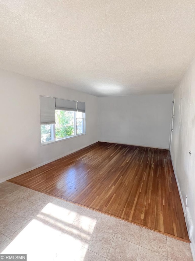 empty room featuring a textured ceiling and light hardwood / wood-style flooring