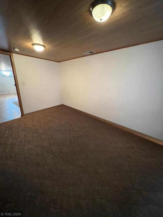 empty room featuring dark colored carpet and wooden ceiling