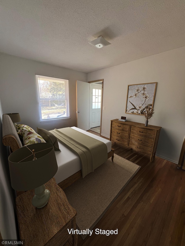 bedroom with dark hardwood / wood-style floors and a textured ceiling