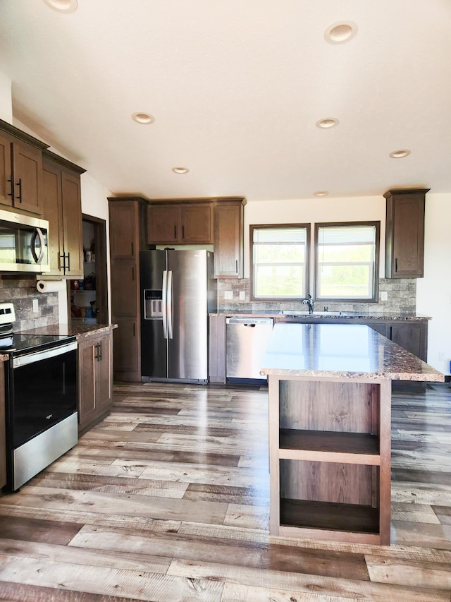 kitchen with hardwood / wood-style floors, appliances with stainless steel finishes, and decorative backsplash