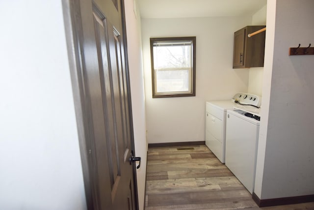 clothes washing area with cabinets, light hardwood / wood-style floors, and washer and clothes dryer