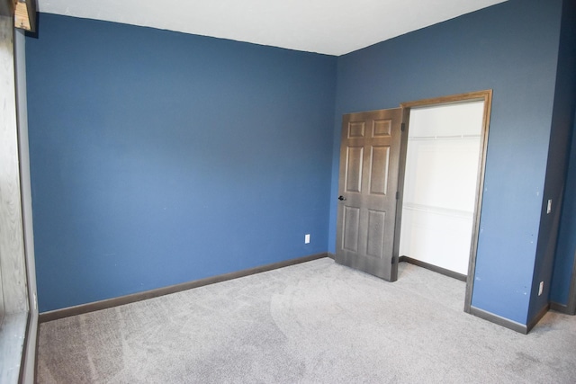 unfurnished bedroom with light carpet and a closet