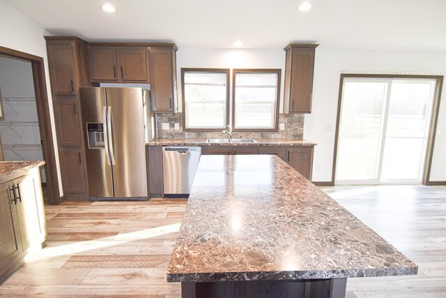 kitchen featuring stainless steel appliances, dark stone countertops, a healthy amount of sunlight, and a center island