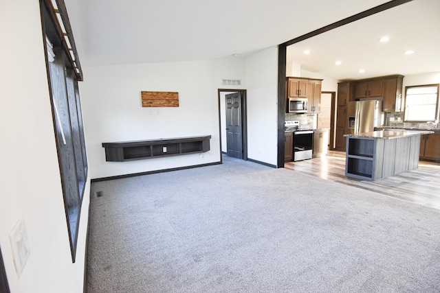 unfurnished living room with light carpet and vaulted ceiling