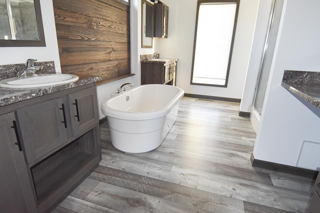 bathroom with hardwood / wood-style flooring, vanity, and plus walk in shower