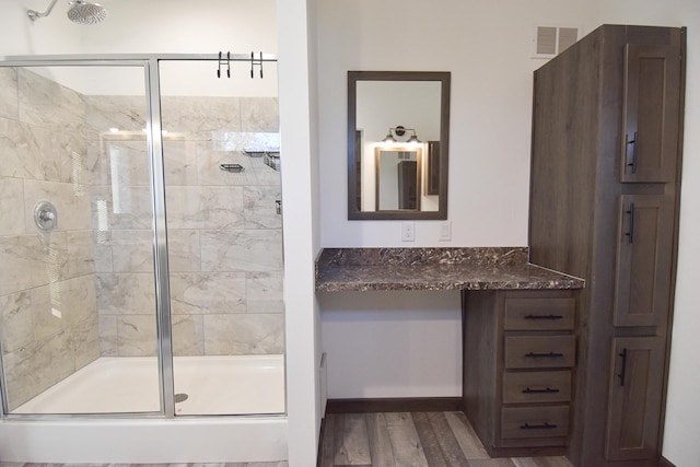 bathroom featuring hardwood / wood-style flooring, a shower with door, and vanity