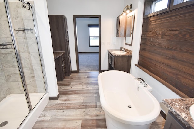 bathroom with hardwood / wood-style flooring, vanity, and shower with separate bathtub